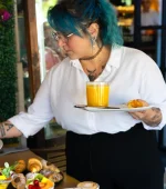ragazza serve colazione al tavolo